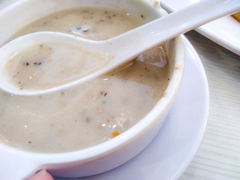 Penang, Malaysia 

Close up of mushroom soup in a plastic bowl. On its surface is a plastic spoon.
