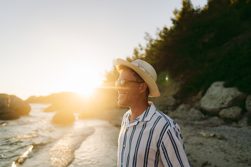 Photo of a mid adult man, enjoying view of the sea at sunset
