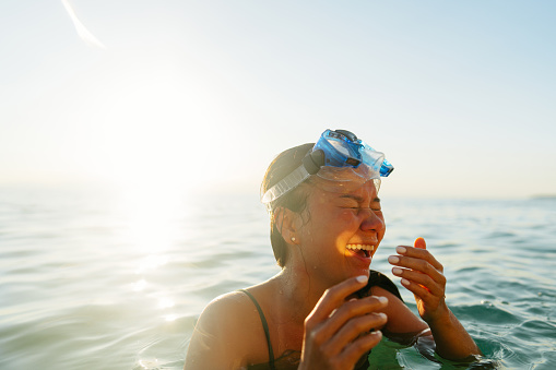 Photo of young Vietnamese woman, wearing a swimming goggles while swimming in the calm sea water