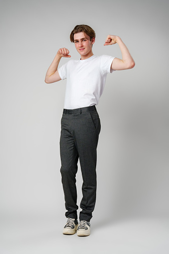 A young man is shown flexing his muscles in front of a plain white background. He stands with arms raised, showcasing his biceps and chest with determination and strength.