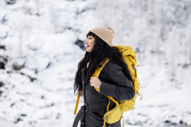 Adventurous Woman with Yellow Backpack Hiking in Snow
