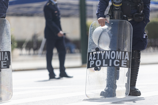 Low section shot of unrecognizable riot policemen with shields standing on street during parade on National Anniversary of Greece