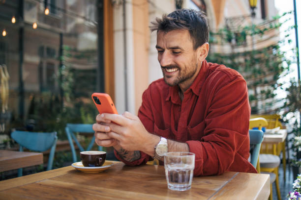 istock Satisfied modern man in stylish casual clothes is using smartphone and enjoying coffee 2148789530