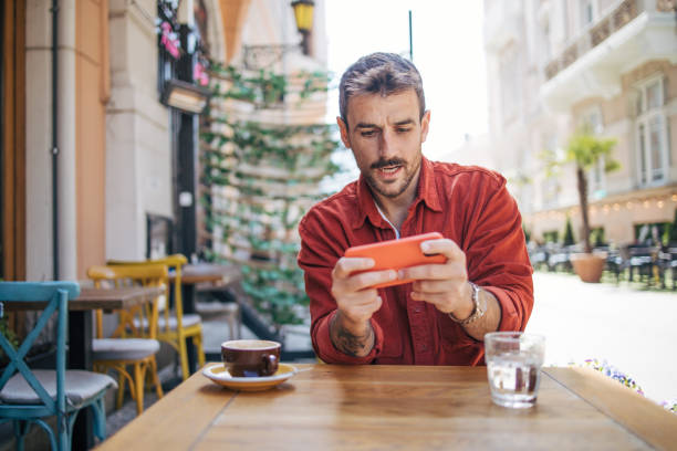 istock Man playing video games on smartphone at coffee shop 2148789625