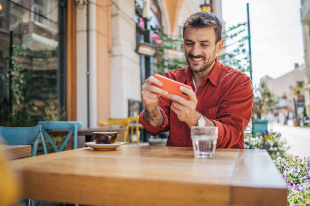 istock Man playing video games on smartphone at coffee shop 2148789629
