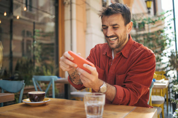 istock Man playing video games on smartphone at coffee shop 2148789630