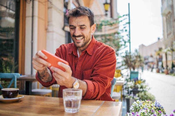 istock Man playing video games on smartphone at coffee shop 2148789687