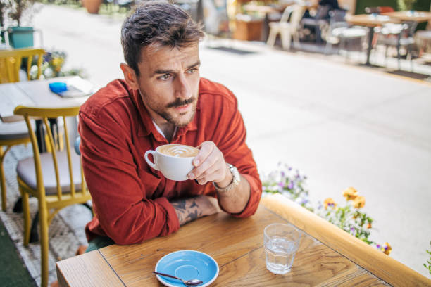 istock Young man sitting in a cafe, having a hot cappuccino 2148789713