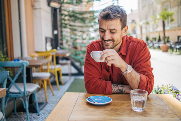 istock Young man sitting in a cafe, having a hot cappuccino 2148789780