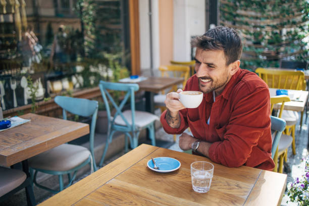 istock Young man sitting in a cafe, having a hot cappuccino 2148789845