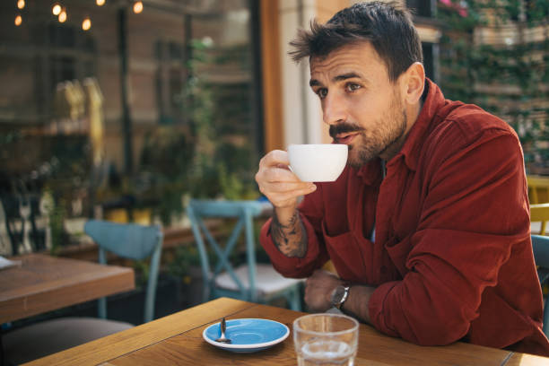 istock Young man sitting in a cafe, having a hot cappuccino 2148789862