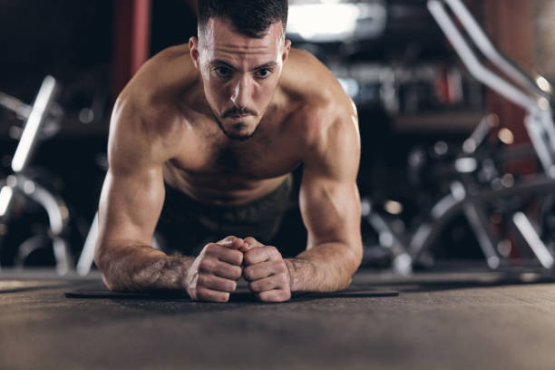 istock Muscular build man exercising endurance in plank position in a gym. 2148789876