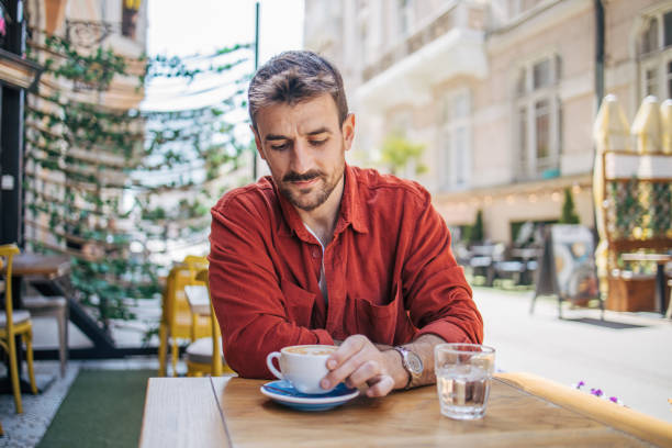 istock Young man sitting in a cafe, having a hot cappuccino 2148789892