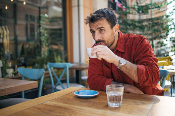 istock Young man sitting in a cafe, having a hot cappuccino 2148790026