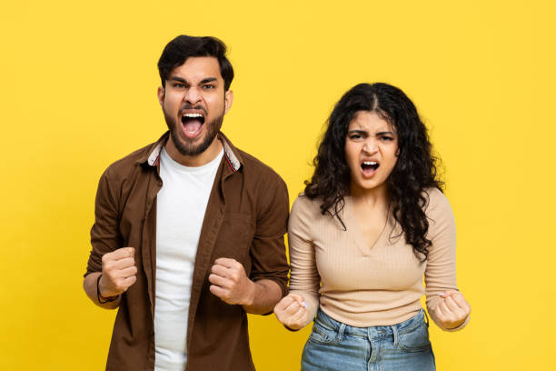 Enthusiastic Young Couple Celebrating Success On Yellow Background