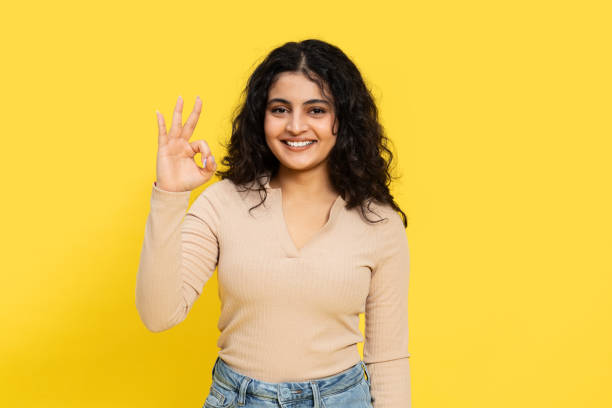 istock Confident Woman Gesturing Okay Sign on Yellow Background 2148790093