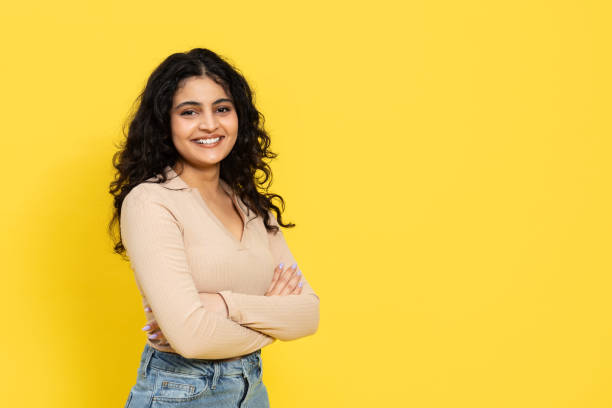 istock Confident Young Woman Smiling Against Yellow Background 2148790097