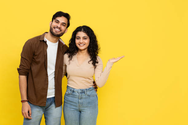 istock Smiling Indian Couple Pointing Together Against Yellow Background 2148790104