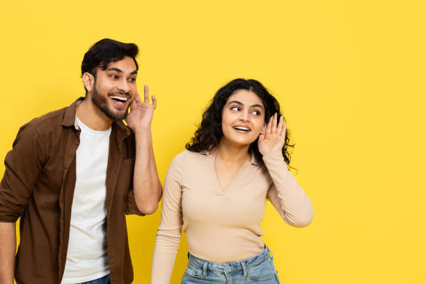 istock Cheerful Young Couple Gossiping on a Bright Yellow Background 2148790116