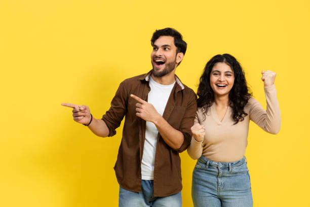 istock Excited Couple Celebrating Success On Yellow Background 2148790137