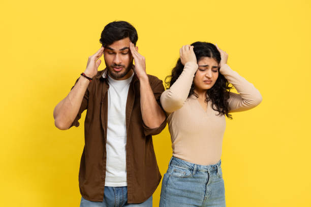 istock Stressed Young Couple With Headaches Against Yellow Background 2148790138