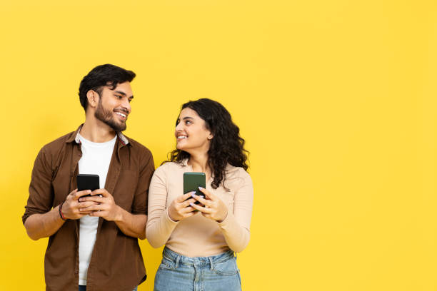 istock Young Couple Using Smartphones On Yellow Background 2148790169
