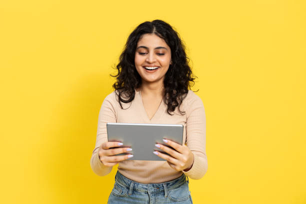 istock Happy Young Woman Using Tablet On Yellow Background 2148790176