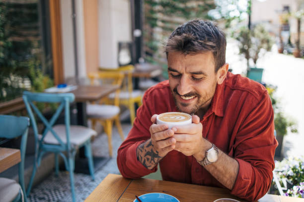 istock Young man sitting in a cafe, having a hot cappuccino. 2148790185