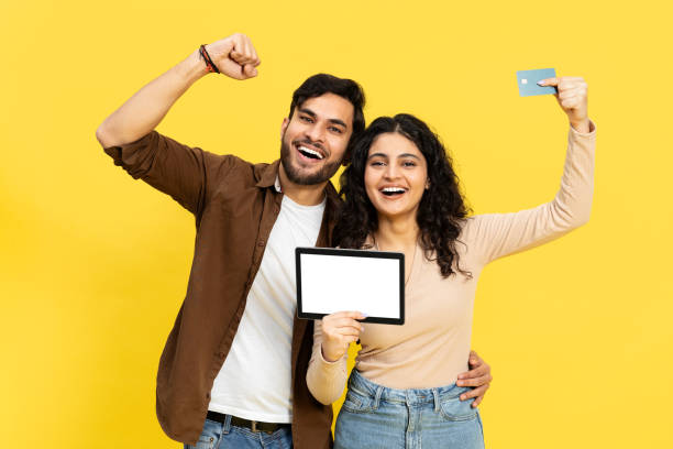 istock Successful Young Couple Holding Card and Tablet on Yellow 2148790192