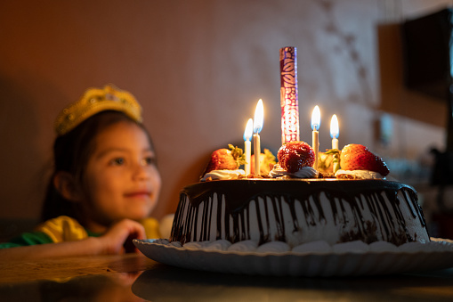 5 year old Mexican girl celebrating her birthday in front of a cake