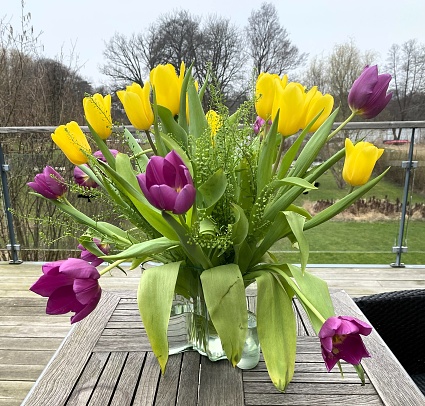 A bunch of tulips arranged on a patio table.