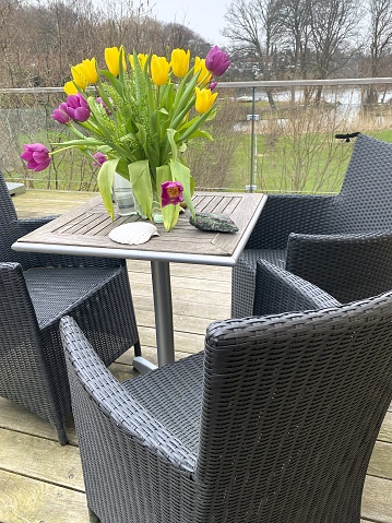 A bunch of tulips arranged on a patio table.