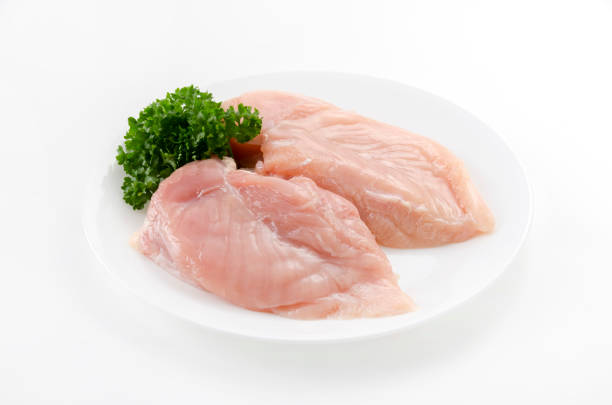istock Raw Chicken breast with parsley on a  dish on white background 2148792195