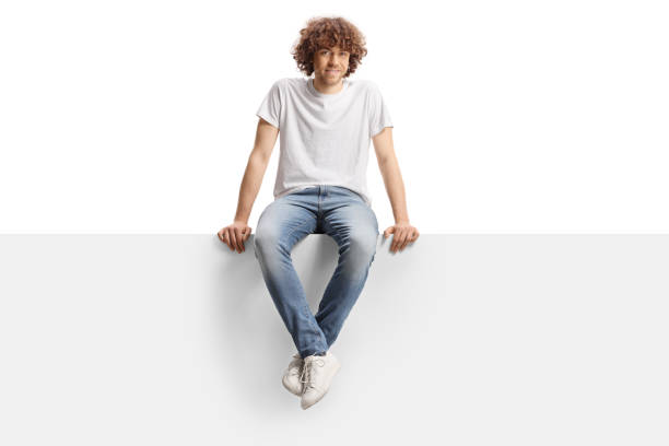 istock Cute guy with curly hair sitting on a blank panel 2148793697