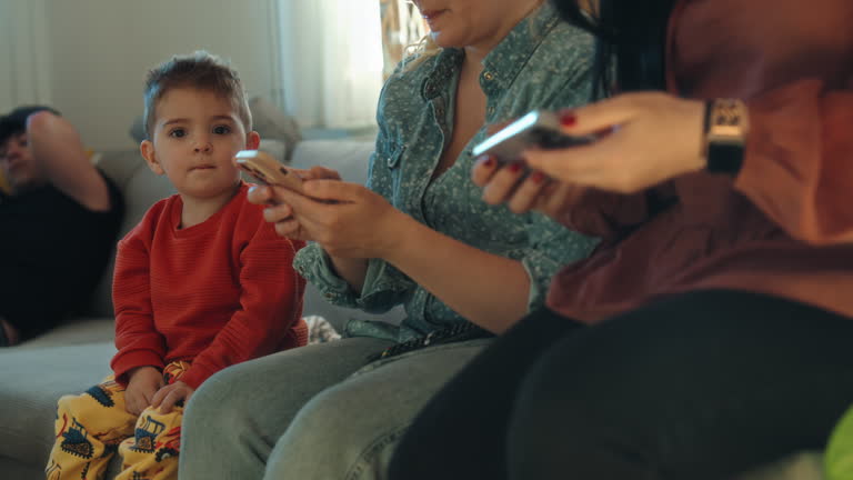 Friends Using Phones While Sitting With Baby Boy At Home