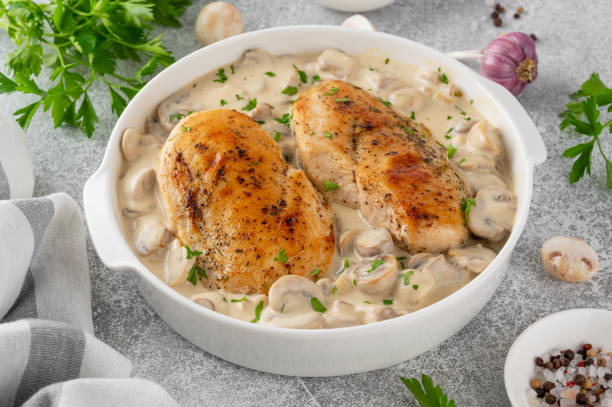 istock Roasted chicken breast with mushrooms in cream sauce on a white ceramic form on a gray concrete background. Comfort food. Top view. 2148795341