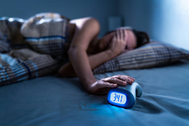 Insomnia and sleep. Sleepless woman. Bad night. Trouble and disorder in bed. Dream problem or lack. Alarm clock. Not asleep, lying awake. Anxiety or nightmare. Sad girl with stress or pain.