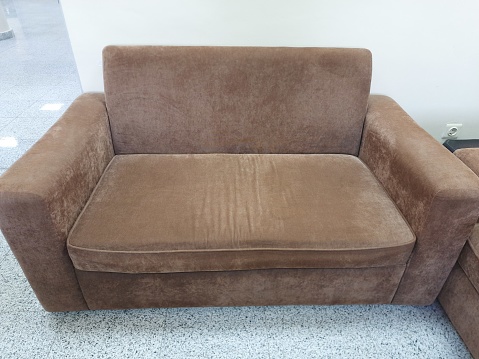 comfortable brown sofa, a yellow wall, and a gray marble floor