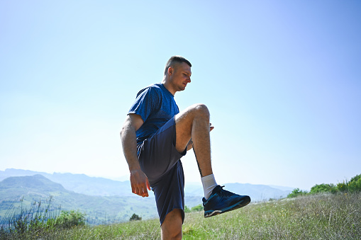 Portrait of a male runner warming up in nature.