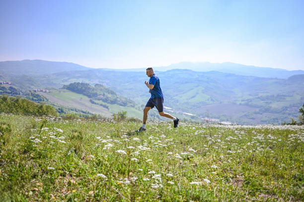 coureur courant dans un paysage rural par une journée ensoleillée. - track and field 30s adult athlete photos et images de collection