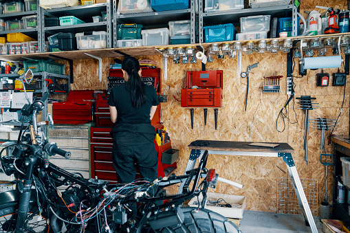 Mid adult female mechanic in her small business motorcycle garage in Japan