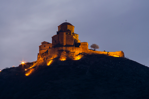 Jvari Monastery on top of the mountain early in the morning. Illuminated with warm light against the morning sky. Mtskheta city, Georgia.