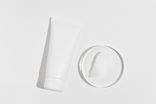 White cream tube mockup and smear sample on glass on white isolated background. The concept of natural cosmetics for moisturizing and nourishing the skin