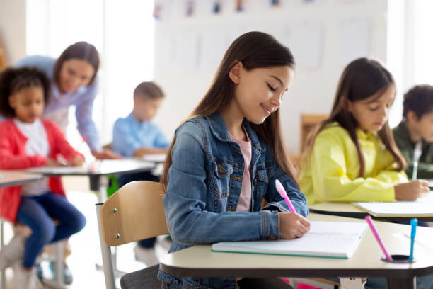 istock Engaged school children sit at desks, writing in their copybooks, creating studious atmosphere in classroom interior 2148800950