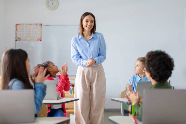 istock Pupils applaud to female teacher, sitting at desks with laptops, showcasing supportive learning environment where technology meets appreciation for inspiring education 2148801189