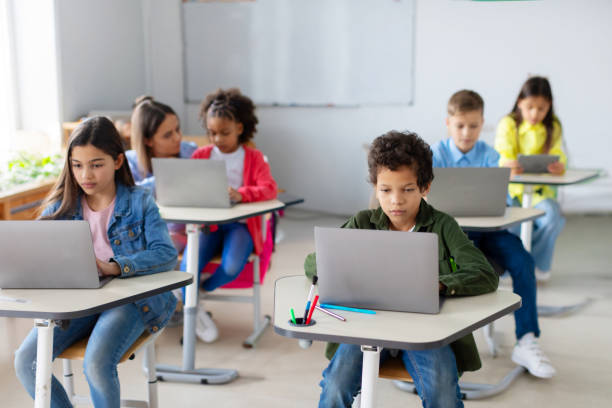 istock Diverse school children sitting at desks with laptops, studying using digital gadgets. Modern elementary education concept 2148802307