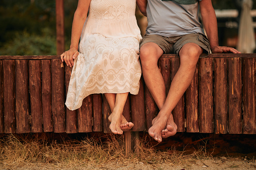 Senior couple enjoying sunrise on a beach vacation. Close-up of their legs. Active seniors. Unrecognizable people.