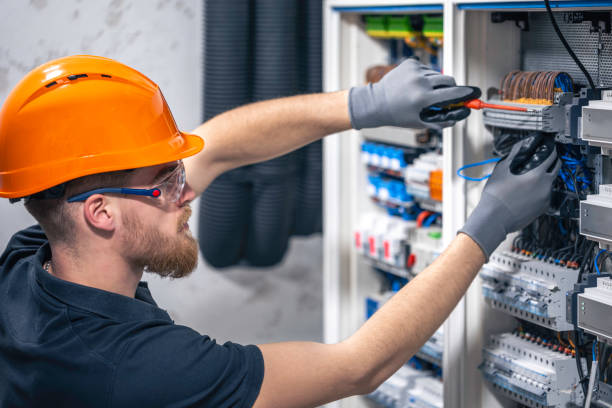 Male electrician working in a switchboard with fuses.