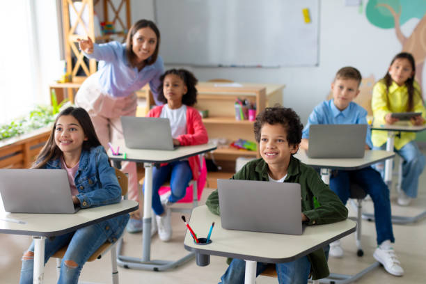 istock School children using laptops, female teacher pointing at blackboard during exam test at computer science class. Modern education 2148804133
