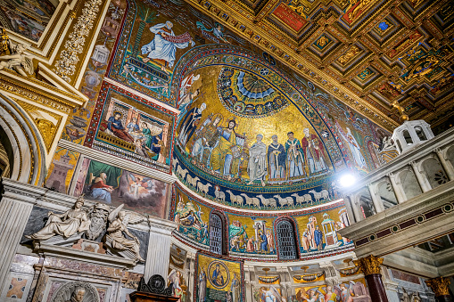 A splendid view of the mosaics decorating the apse inside the ancient Basilica of Santa Maria in Trastevere (Our Lady in Trastevere), in the historic heart of Rome. This Romanesque-style basilica, founded by Pope Callixtus I around 220 AD, is one of the oldest churches in Rome. In the upper part of the apse a 12th century mosaic depicts the Virgin and Christ seated on the same throne, while the mosaics in the lower part of the apse depict the life of the Virgin Mary, by the medieval artist Pietro Cavallini (1259–1330). Trastevere is an iconic district of the Eternal City, due to the presence of countless artistic and historical treasures, monuments and ancient Romanesque and Baroque churches, but also for its squares and alleys to be explored freely, where it is easy to find typical restaurants, pubs, small shops of artisans and scenes of daily life with the original Roman soul. In 1980 the historic center of Rome was declared a World Heritage Site by Unesco. Wide angle image in high definition quality.